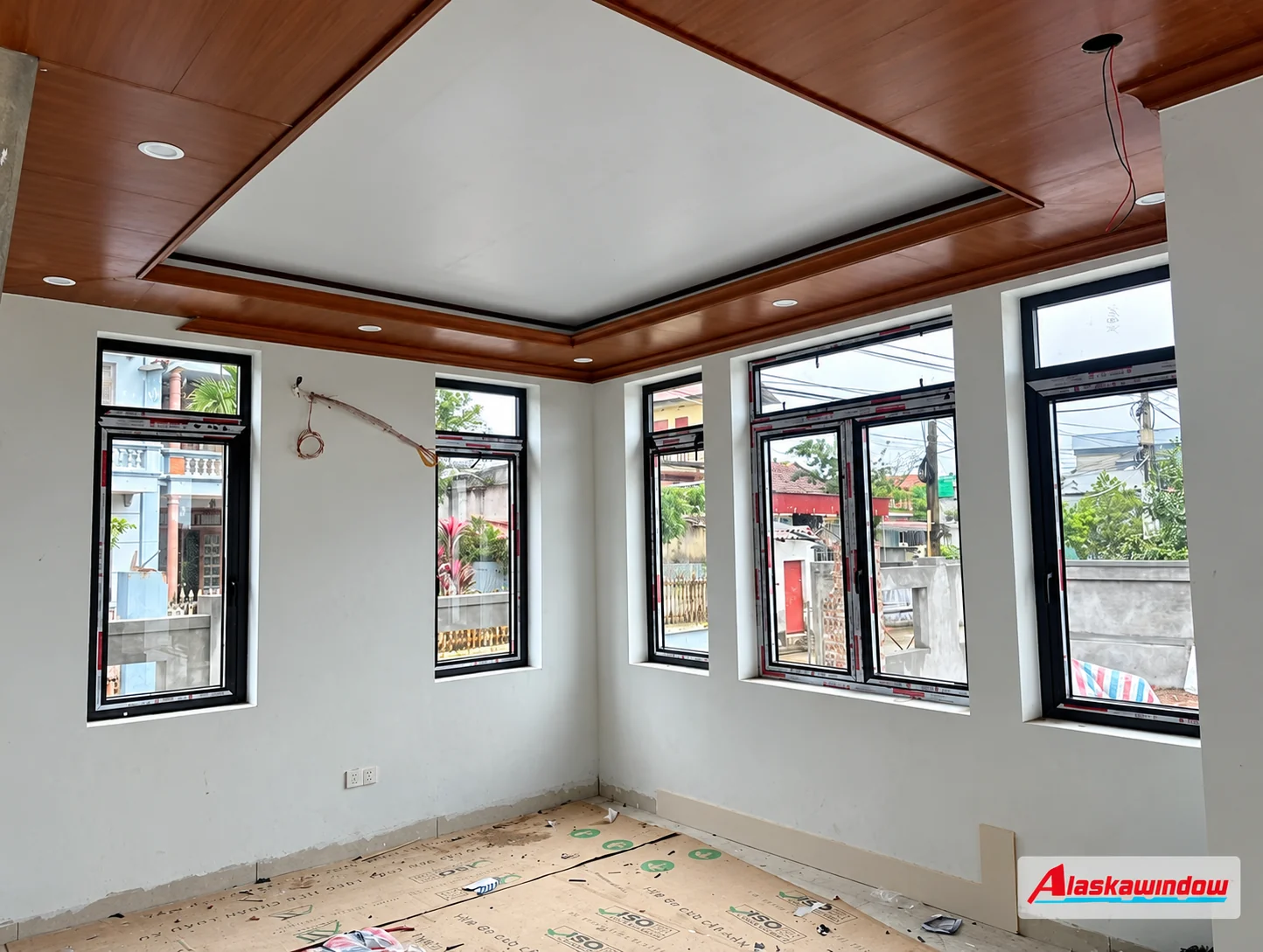 Các ô cửa sổ nhôm kính trên hai mặt tường trong phòng đang hoàn thiện