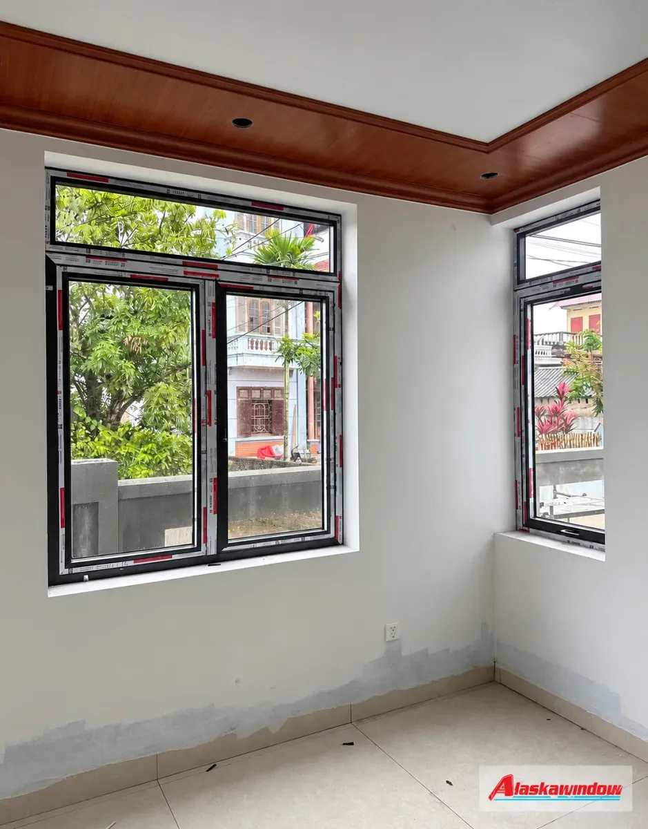 Cửa sổ nhôm màu tối kết hợp ô kính ngang phía trên tại góc phòng