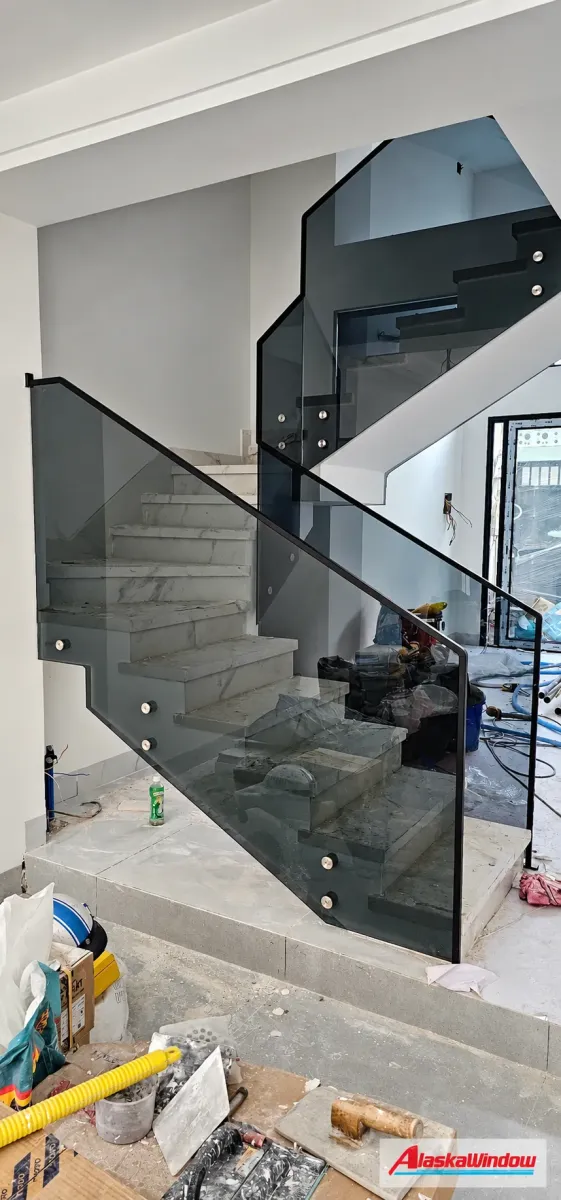 Cầu thang kính sẫm màu với tay vịn tối màu nhìn từ chân thang