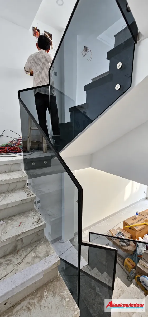 Khu vực cầu thang kính có thợ và dụng cụ trong giai đoạn hoàn thiện công trình