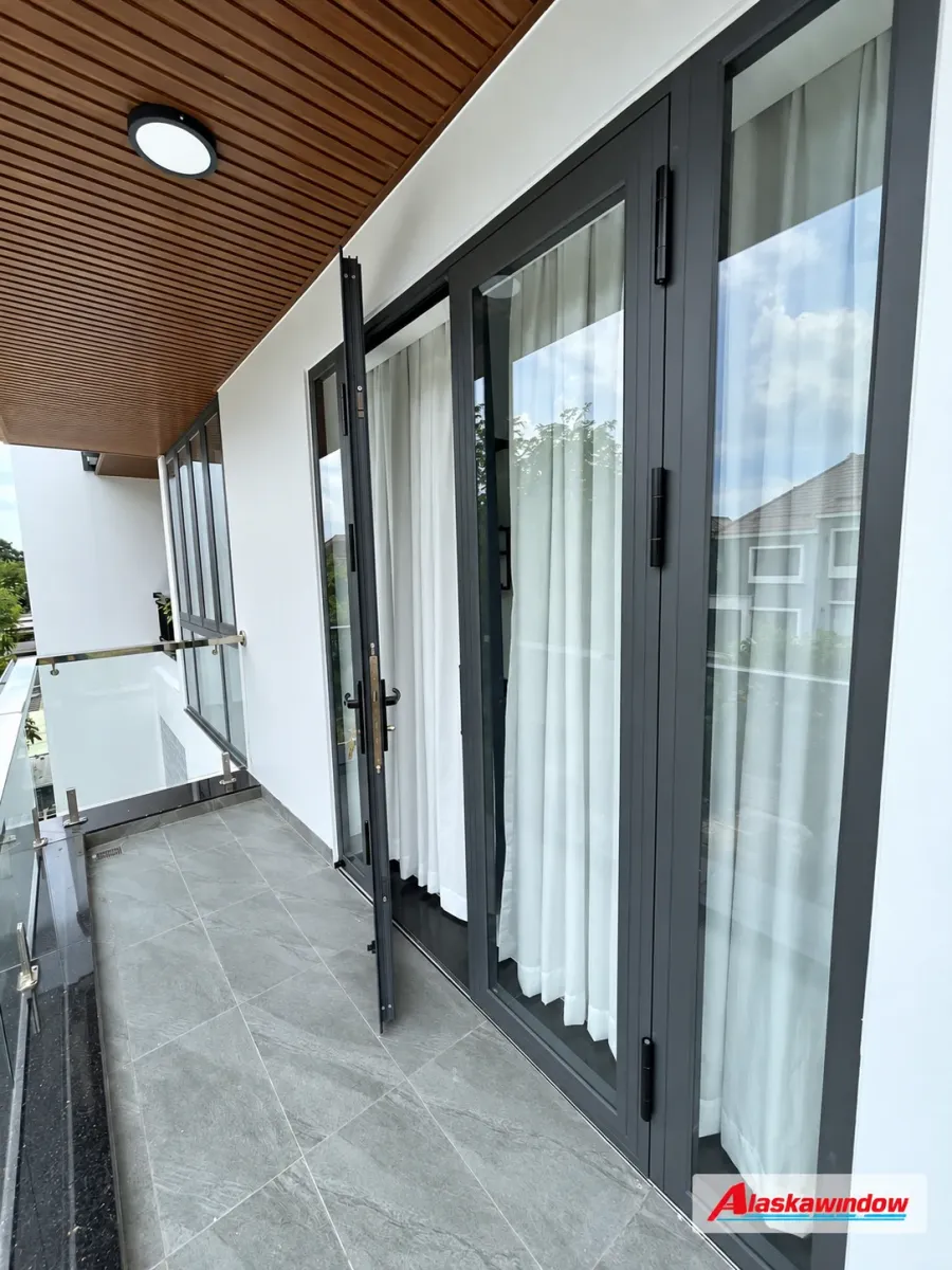 Cửa đi mở quay nhôm xám ghi ra ban công với kính và rèm trắng