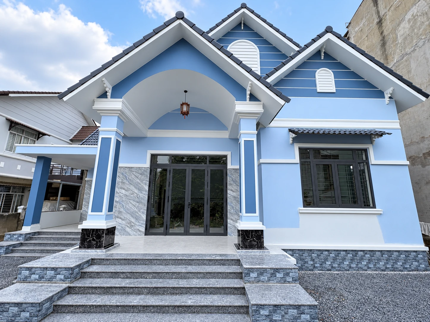 Mặt tiền kết hợp mái ngói xám, tường xanh nhạt và cửa nhôm Xingfa.