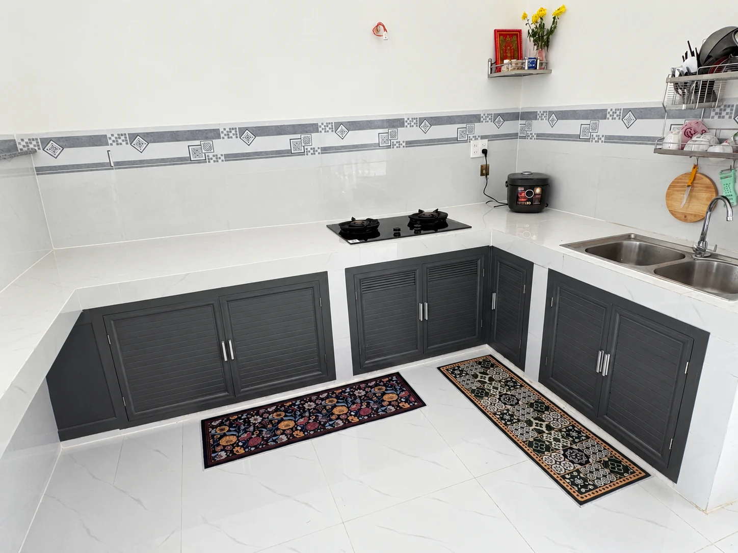 Hệ cánh tủ bếp nhôm màu xám bên dưới mặt bàn sáng màu.