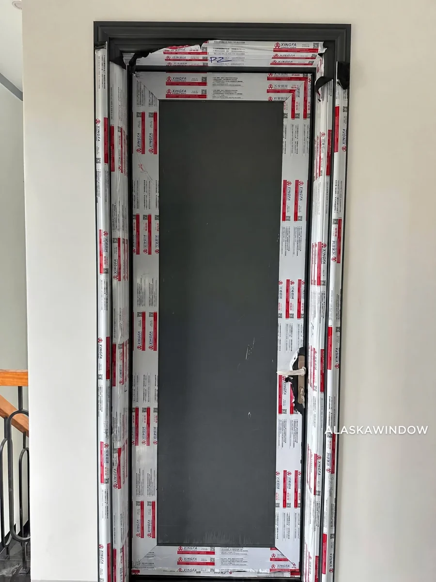 Cửa phòng nhôm tấm màu xám đậm với khung còn màng bảo vệ