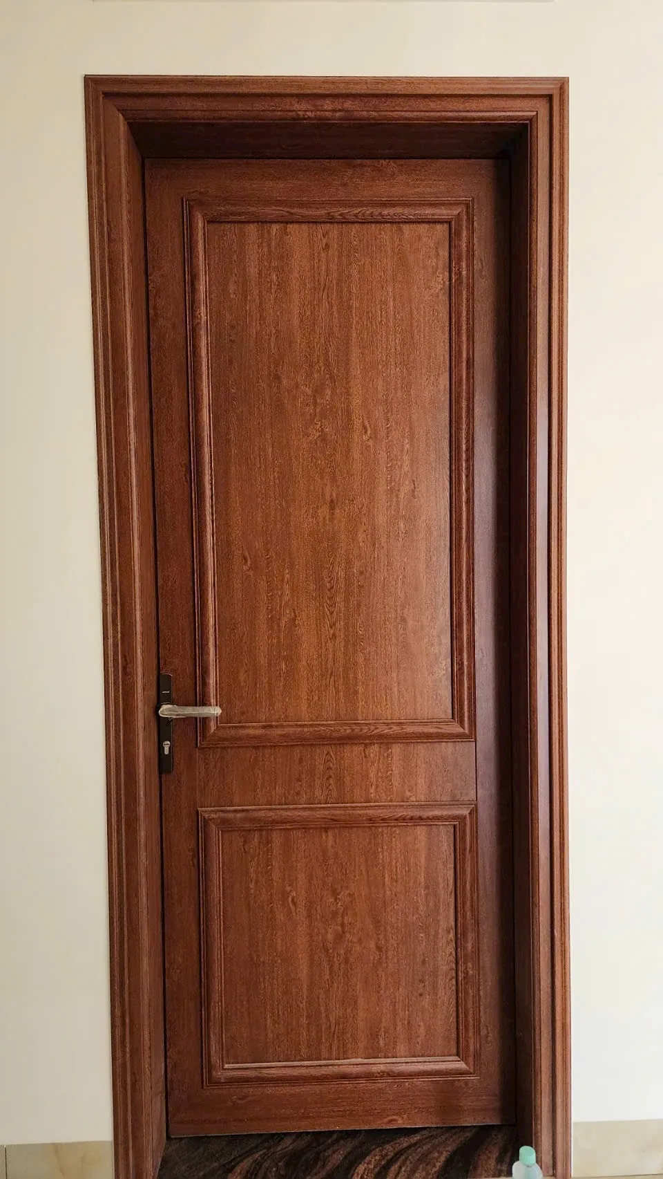 Cửa pano kín màu vân gỗ với đường gờ chia mảng và tay gạt