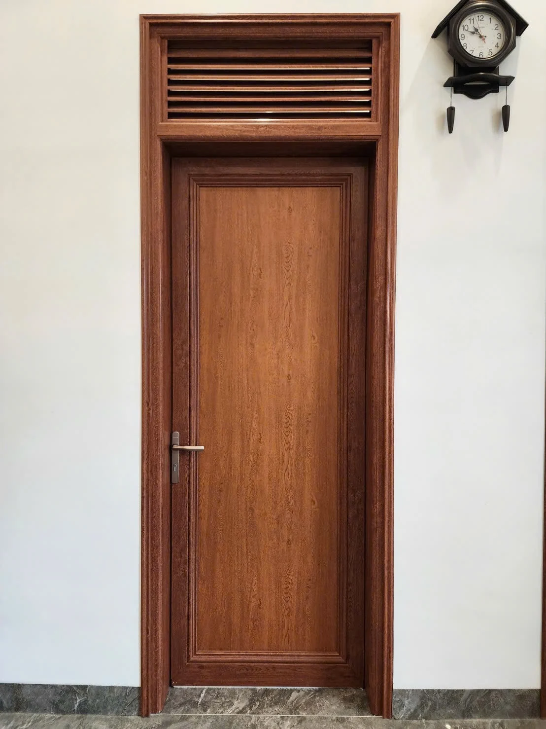 Cửa màu vân gỗ có pano kín và ô thoáng lá sách phía trên